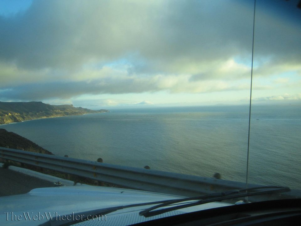 Ocean coastline and headlands seen over a car hood and wiper