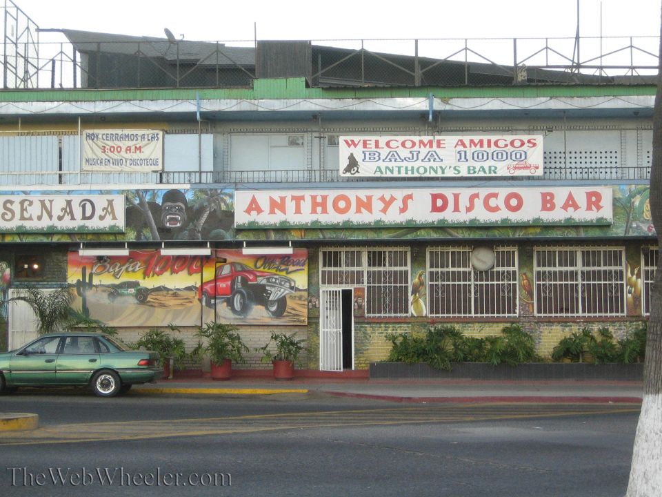 Storefront of Anthony's Disco Bar with Baja 1000 mural and parked sedan