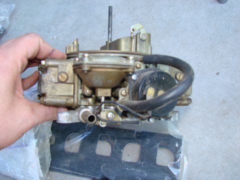 1979 Ford Bronco - Close-up of a Holley carburetor being held, with a black hose connected.