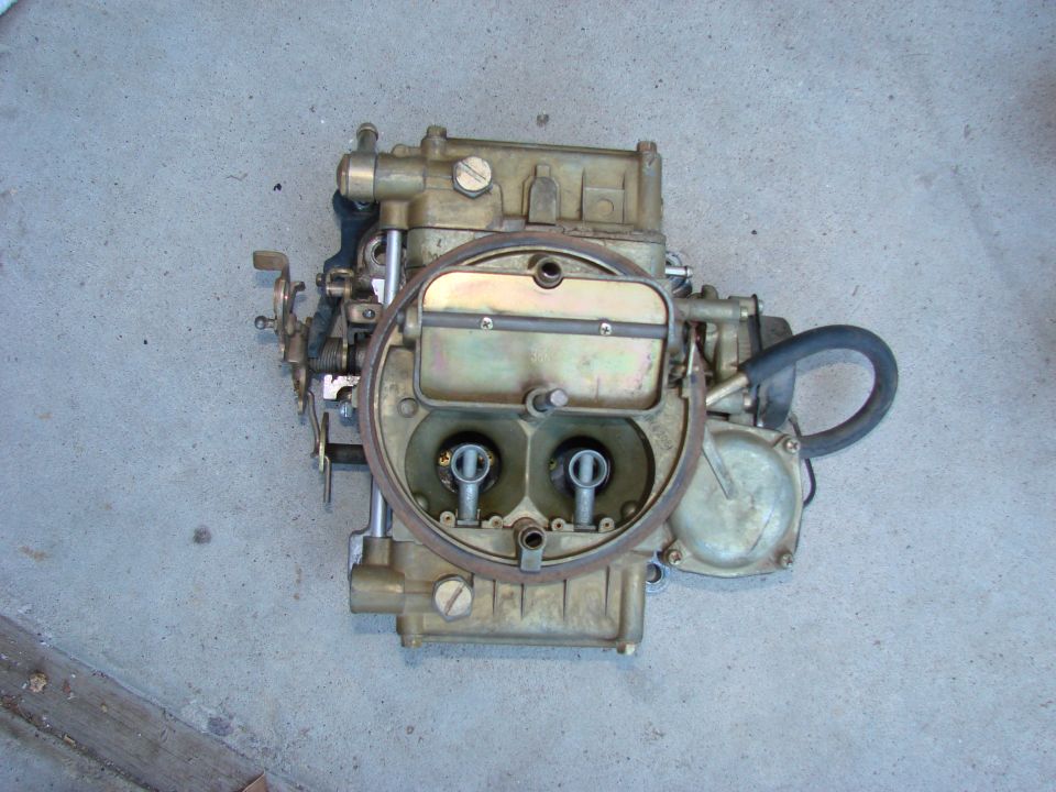 Holley carburetor with two barrels, sitting on a concrete floor
