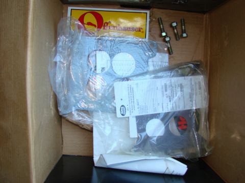 1979 Ford Bronco - Unboxed Offenhauser intake manifold parts, including a sticker and warranty information, are laid out in a cardboard box.