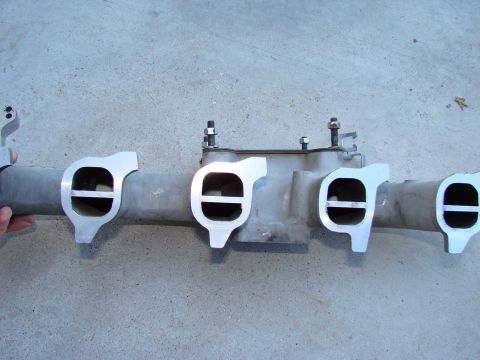 1979 Ford Bronco - Close-up of an aftermarket intake manifold, likely for a V8 engine, resting on concrete.