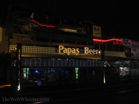 1990 Ford Bronco - multi-level Papas and Beer nightclub glows with red neon trim and interior lights against a dark night sky.