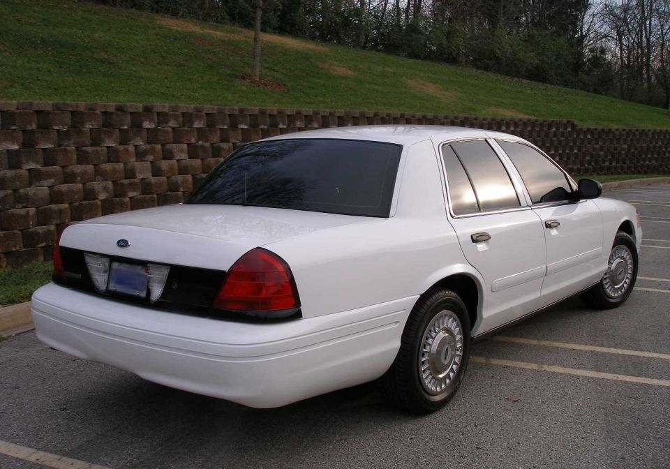 White 2001 Ford Crown Victoria parked on asphalt, facing away from the camera