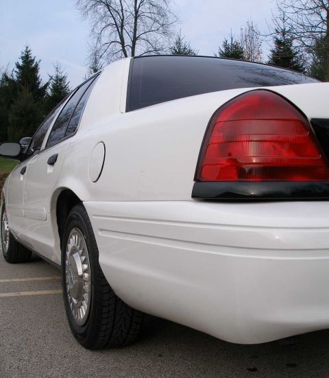 2001 Ford Crown Victoria - Rear view of a white 2001 Ford Crown Victoria, showing its distinctive taillight and body lines.