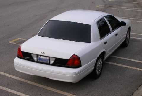 2001 Ford Crown Victoria - The rear of a white 2001 Ford Crown Victoria is visible from a high angle in a parking lot.