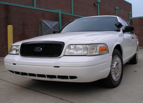 2001 Ford Crown Victoria - This white 2001 Ford Crown Victoria is shown from the front, parked in front of a brick building.