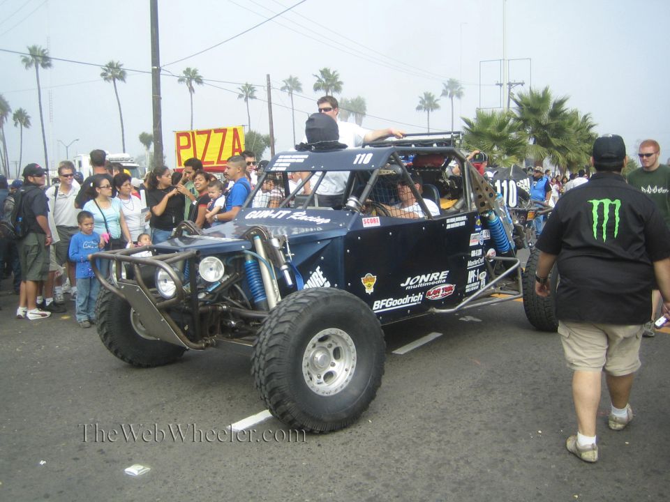 Dark blue open-frame off-road buggy 110 driving through a crowded street