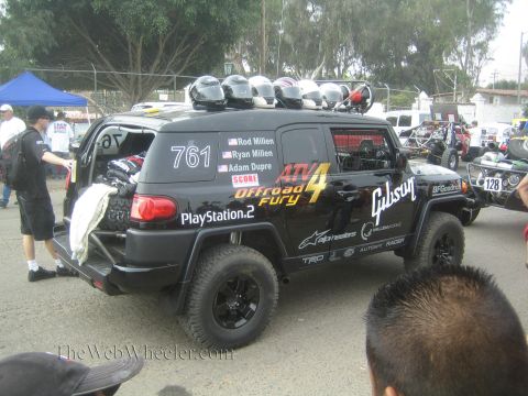 1990 Ford Bronco - black Toyota FJ Cruiser race vehicle '761' carries helmets on its roof and sponsor decals including Gibson and PlayStation 2.