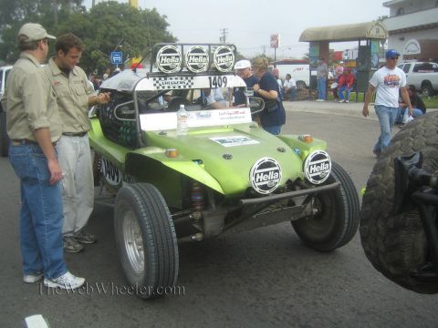 1990 Ford Bronco - green fiberglass dune buggy numbered 1409 with twin Hella driving lights, crew members standing alongside.