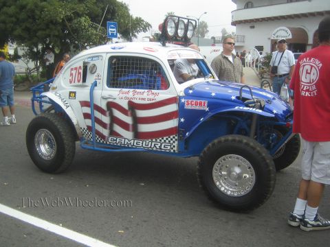 1990 Ford Bronco - red, white and blue stars-and-stripes Baja Bug race car numbered 576 with Camburg and Junk Yard Dogs graphics.