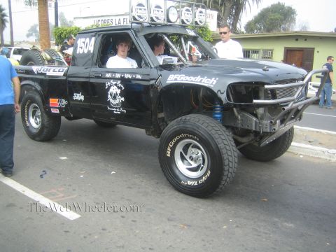 1990 Ford Bronco - black single-cab off-road prerunner race truck numbered 1504 with exposed long-travel front suspension on a street.