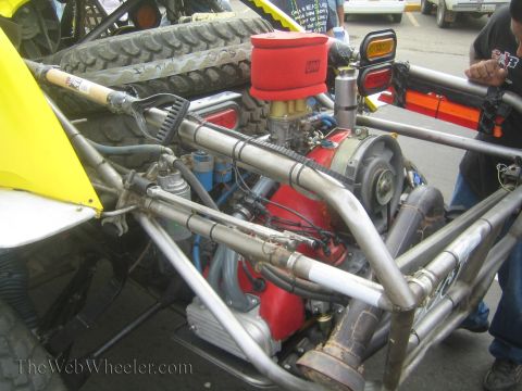 1990 Ford Bronco - Close view of a tube-frame race buggy's exposed mid-mounted V-engine with a red air filter and headers.