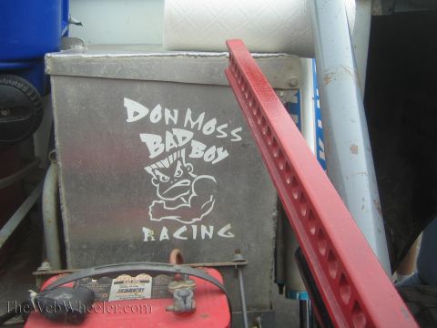 1990 Ford Bronco - scuffed aluminum toolbox lettered Don Moss Bad Boy Racing beside a red metal ramp in a pit area.
