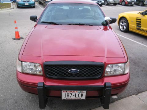 2001 Ford Crown Victoria - The front of a red Ford Crown Victoria is shown, parked next to a yellow Ford Mustang.