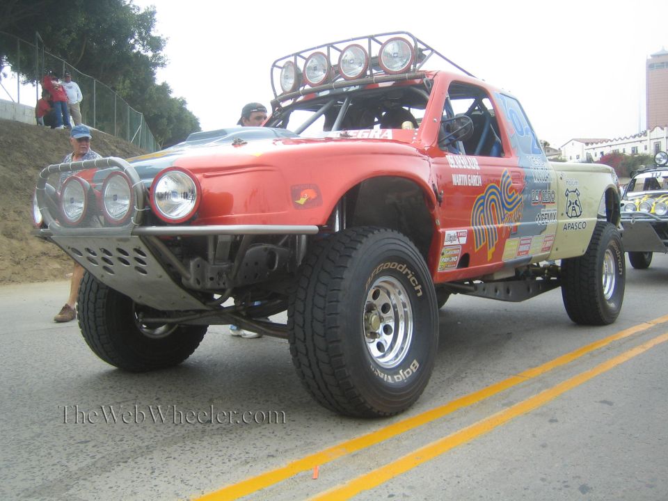 Red off-road race truck with roof light bar parked on an incline