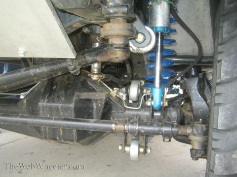 1990 Ford Bronco - Detailed view of a vehicle's undercarriage showing a blue coilover shock, axle and control arms.