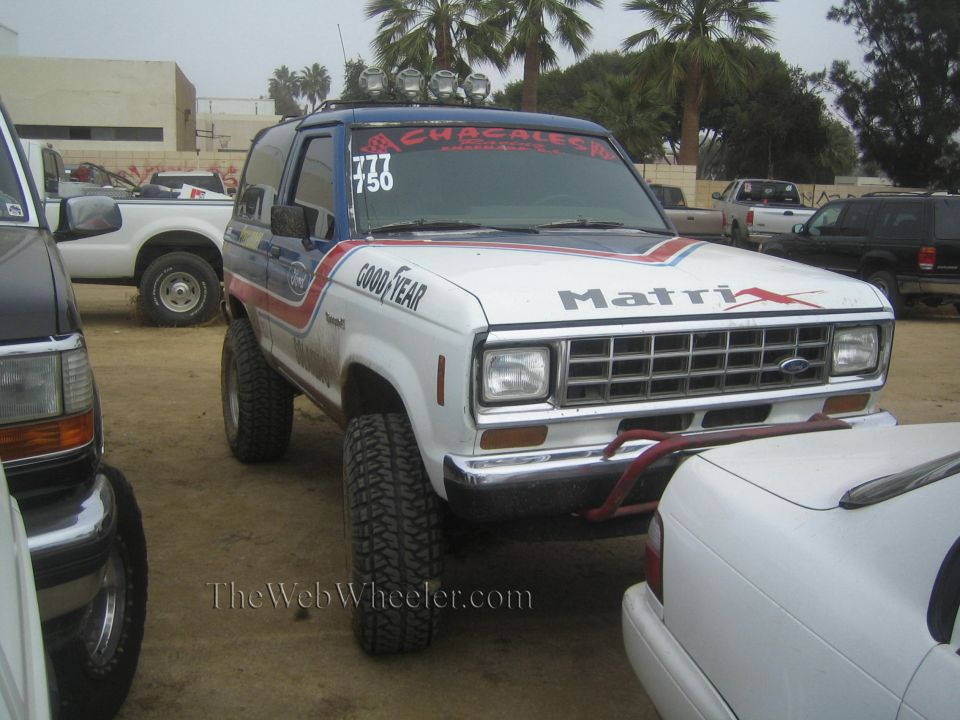 White lifted Ford Bronco II prerunner with Matrix graphics and roof lights, front three-quarter