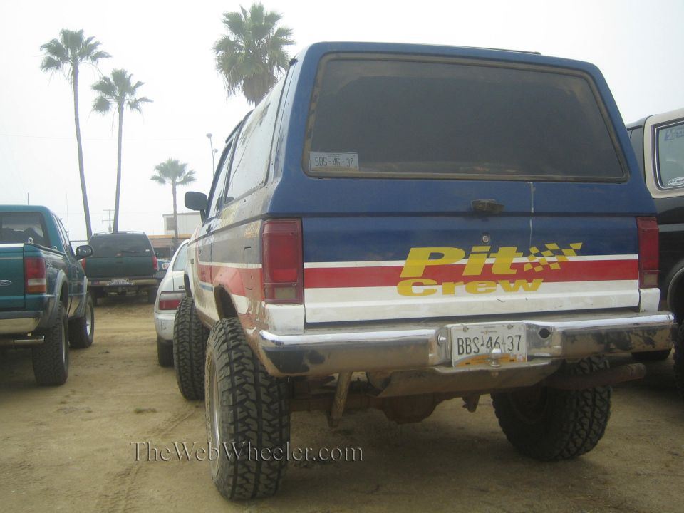 Rear view of blue and white lifted SUV with Pit Crew decal and Baja plate on dirt lot