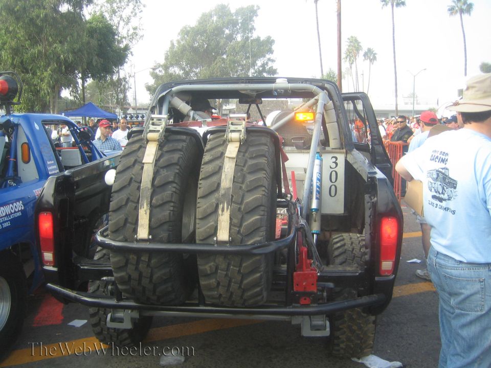 Rear of open tube-frame race truck number 300 carrying two spare mud tires