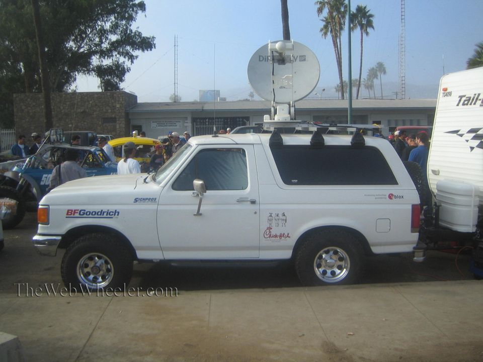 Side view of white Ford Bronco with roof-mounted satellite dish and BFGoodrich decals