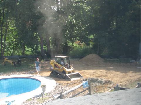 1992 Ford Bronco - A yellow skid steer loader is positioned near a swimming pool under construction, with a man standing nearby.