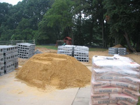 1992 Ford Bronco - Construction materials including sand, cinder blocks, and bagged cement are staged outdoors.