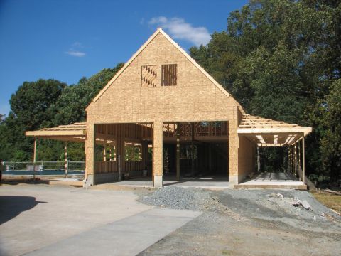 1992 Ford Bronco - A garage is shown during its construction phase, with the wooden framing and roof structure clearly visible against a blue sky.