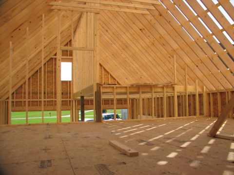 1992 Ford Bronco - The interior of a wooden building under construction shows exposed beams and rafters, with a view of the outdoors through a window.