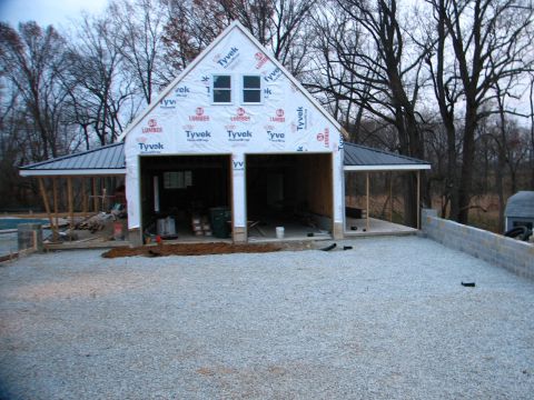 1992 Ford Bronco - A garage is being built, with Tyvek wrap on the exterior and a metal roof, surrounded by trees.