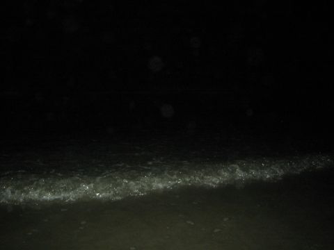 1990 Ford Bronco - very dark nighttime beach scene shows faint surf washing up onto wet sand.