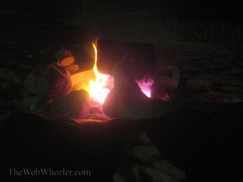 1990 Ford Bronco - People sit silhouetted around a bright orange campfire on a dark beach at night.