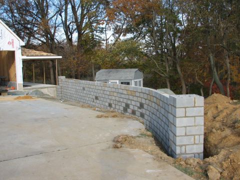 1992 Ford Bronco - A curved concrete block wall is being built next to a driveway, with a shed and trees in the background.