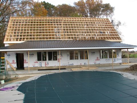 1992 Ford Bronco - Construction site shows a house with new roof framing and exterior wrap, adjacent to a covered pool.