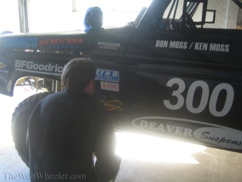 1990 Ford Bronco - man crouches next to the black bodywork of race vehicle 300 lettered Don Moss / Ken Moss with BFGoodrich and Deaver sponsor decals.