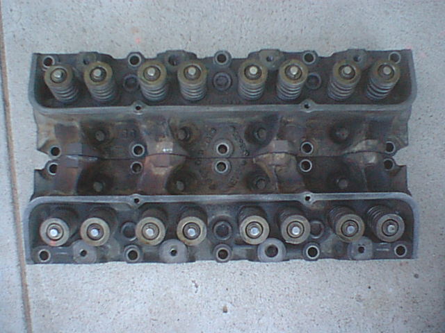 Two cylinder heads showing valve spring side laid on concrete