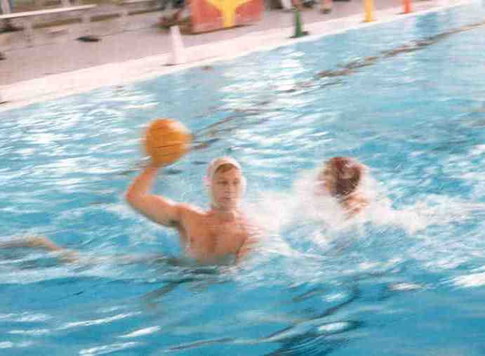 Water polo players in a pool, one holding a ball