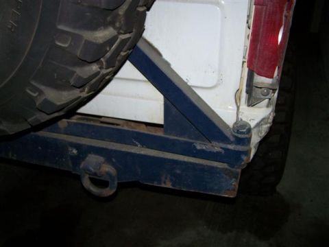 1995 Ford Bronco - The rear of a 1995 Ford Bronco shows a white body with a blue aftermarket bumper and tire carrier.