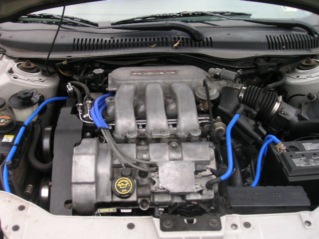 Engine bay with V6 engine, blue hoses, and battery