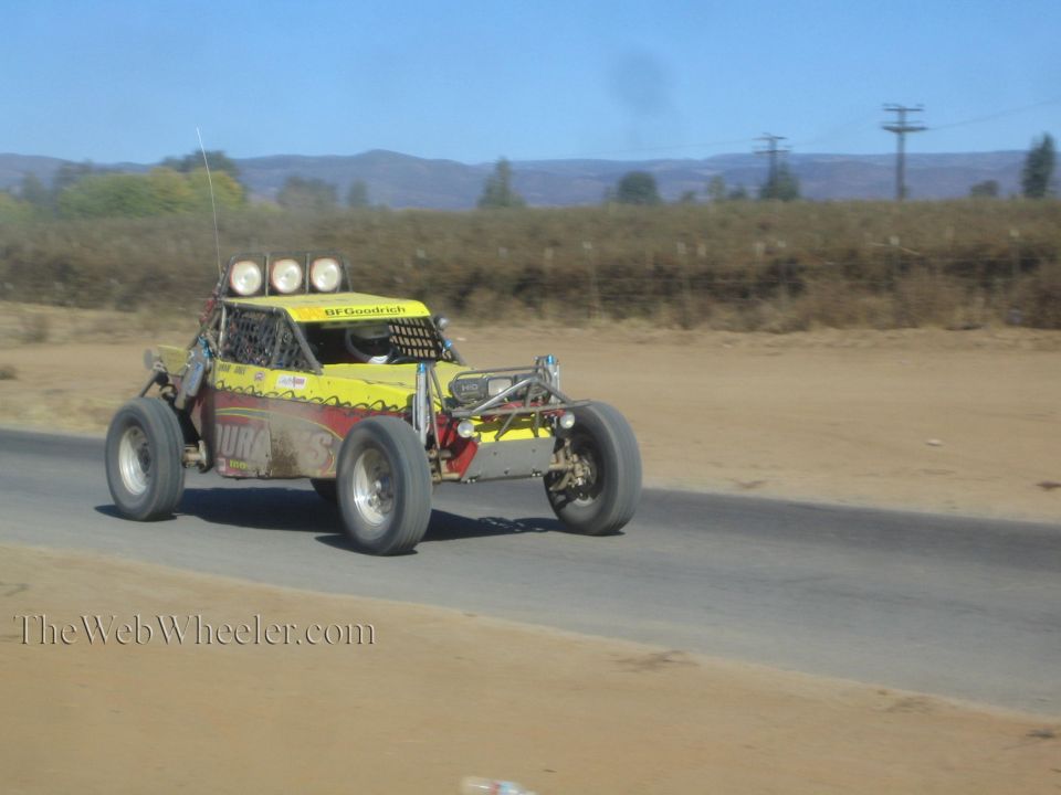 Yellow and red off-road race buggy with roof lights on paved road