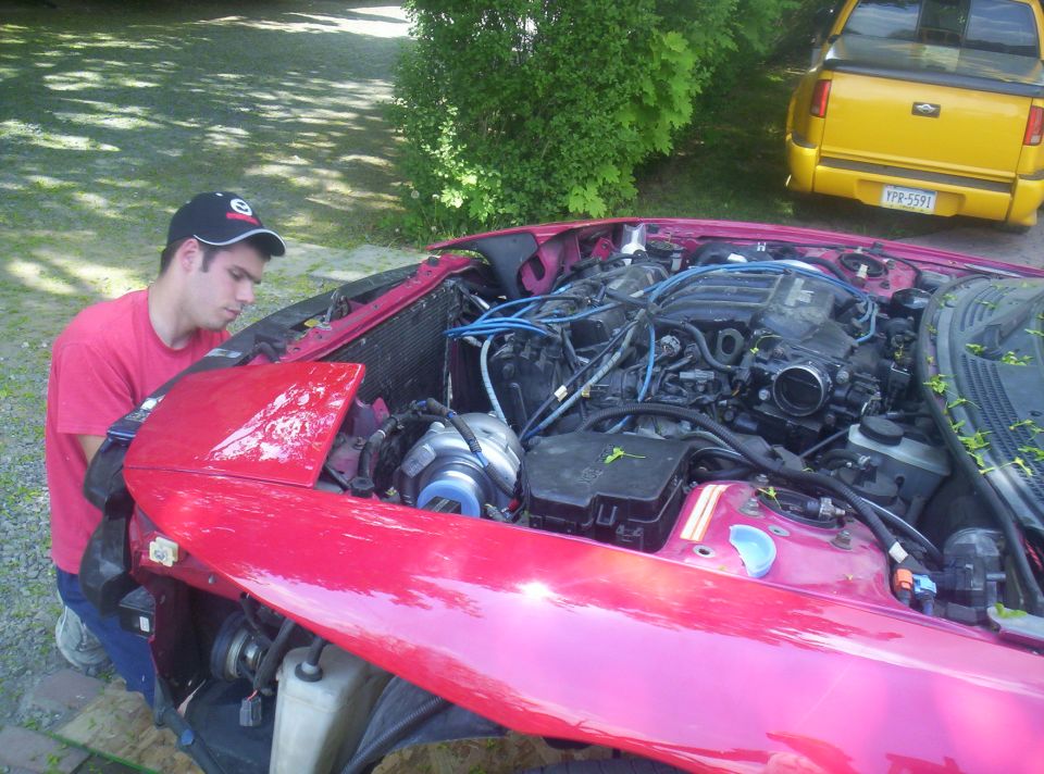 Red 1997 Ford Probe engine bay with a person working on it, front view