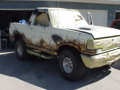1989 Ford Bronco - A Ford Bronco is being prepped for a new paint job, with masking tape covering the front end.