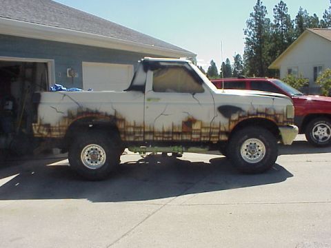 1989 Ford Bronco - A white Ford Bronco with a unique paint job sits parked next to a red vehicle.