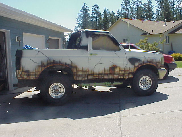 Lifted white Ford Bronco with flame graphics, side view in driveway