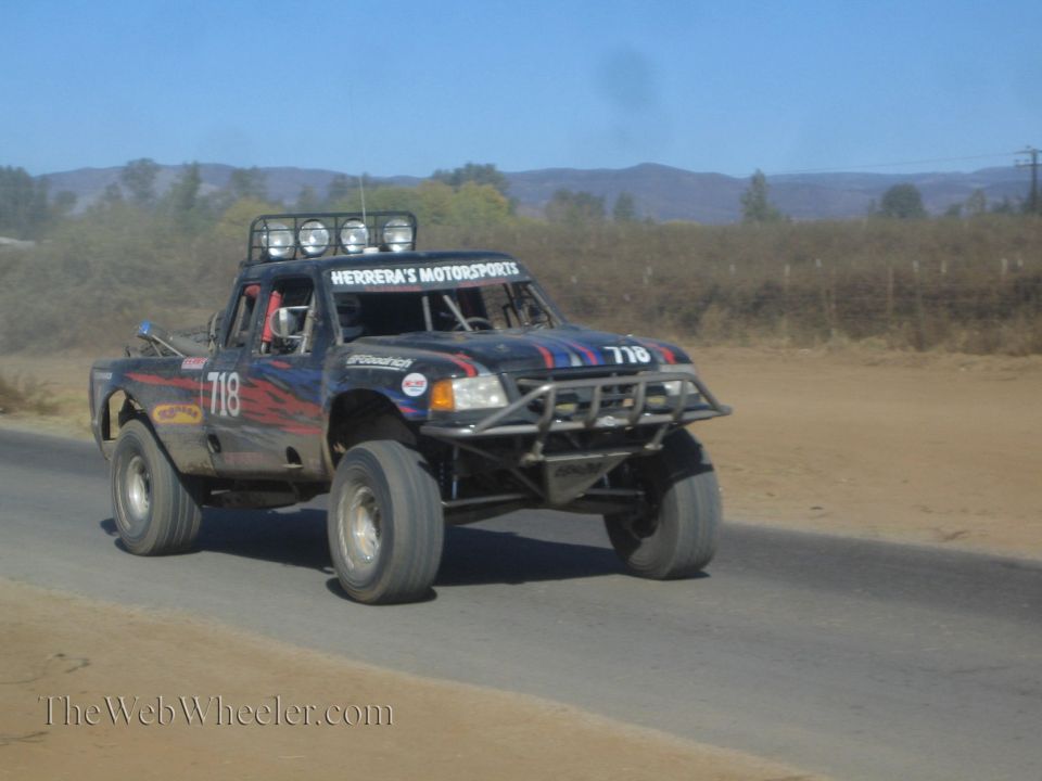 Black off-road race truck number 718 Herrera's Motorsports on road
