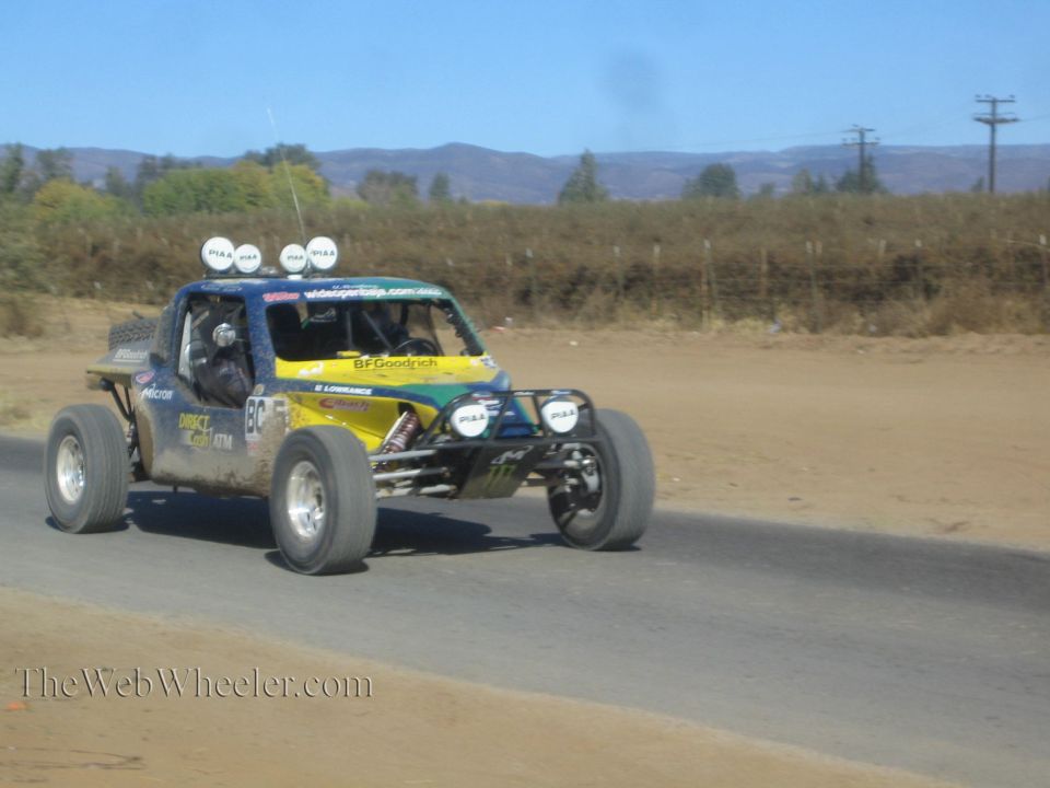 Blue and yellow off-road race buggy with four roof lights on desert road