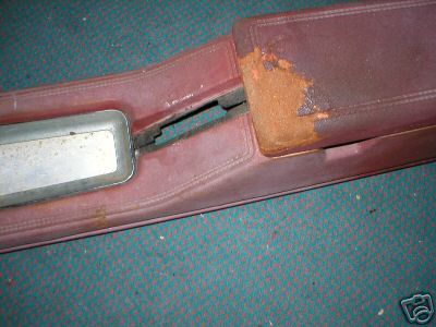 1978 Ford Mustang II - A close-up shows a damaged red car interior part with a metal accent and visible rust.