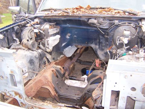 1987 Ford Bronco - The engine bay of a vehicle is shown with the engine removed, revealing the frame and brake system components.