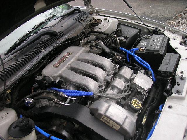 Ford 24 valve V6 engine with blue hoses and a battery visible
