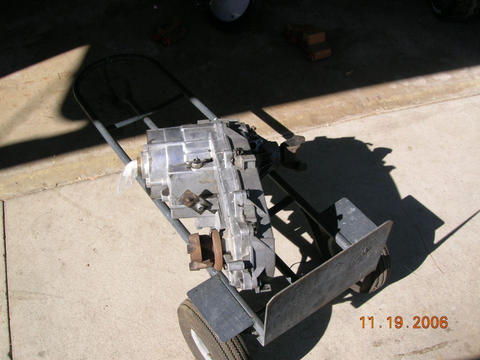 Transfer case on a dolly, silver metal casing, some rust on mounting points